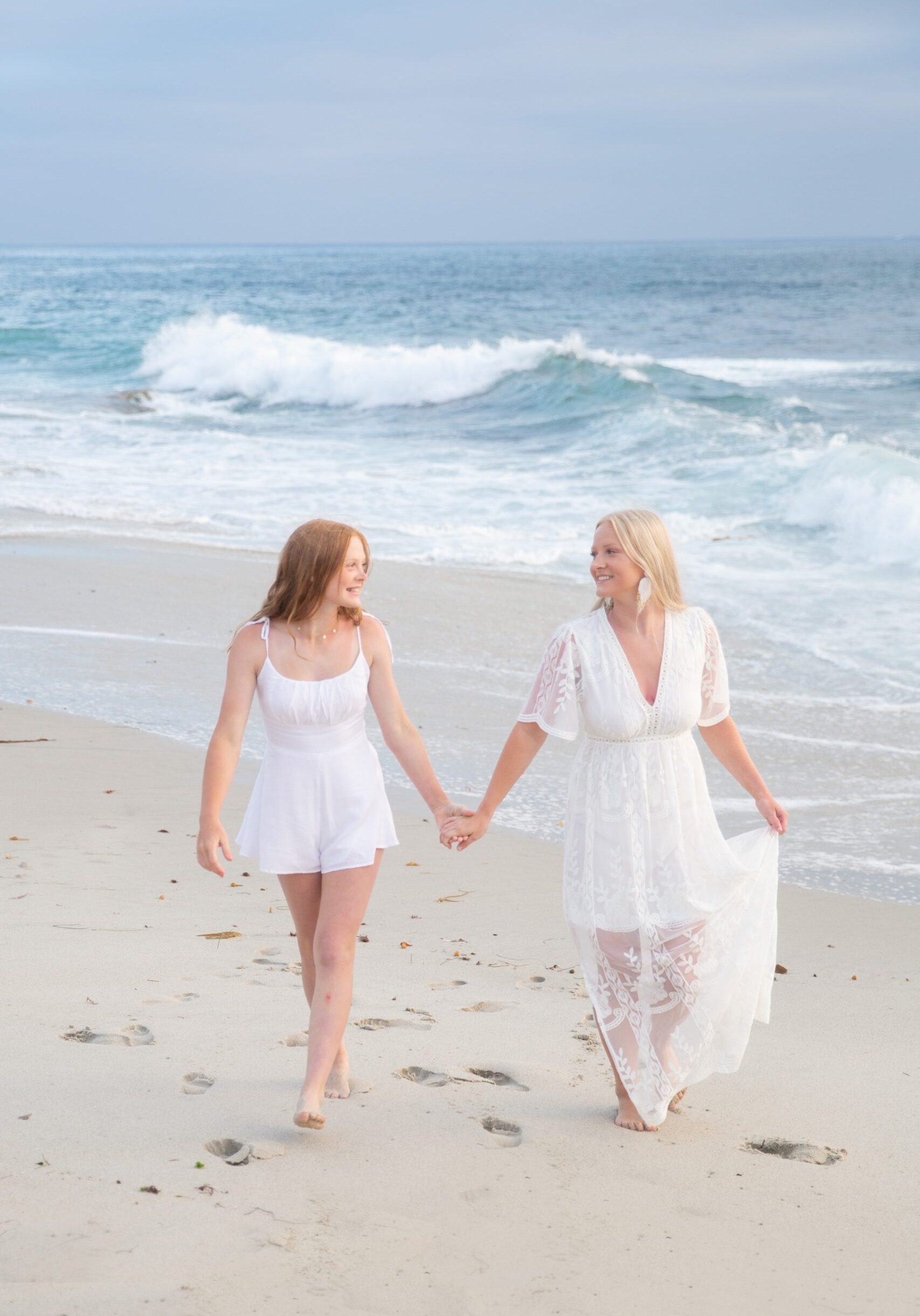 2 ladies walking on a beach holding hands